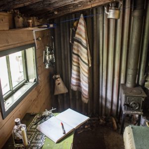 Det er enkelt innreia i hemmelege hytter. Her er ei blikkplate brukt til ein av veggane. Vedomnen sørgjer for varme. Foto: Marius Nergård Pettersen