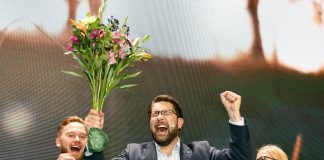 Jimmie Åkesson jublar med bukett i handa.