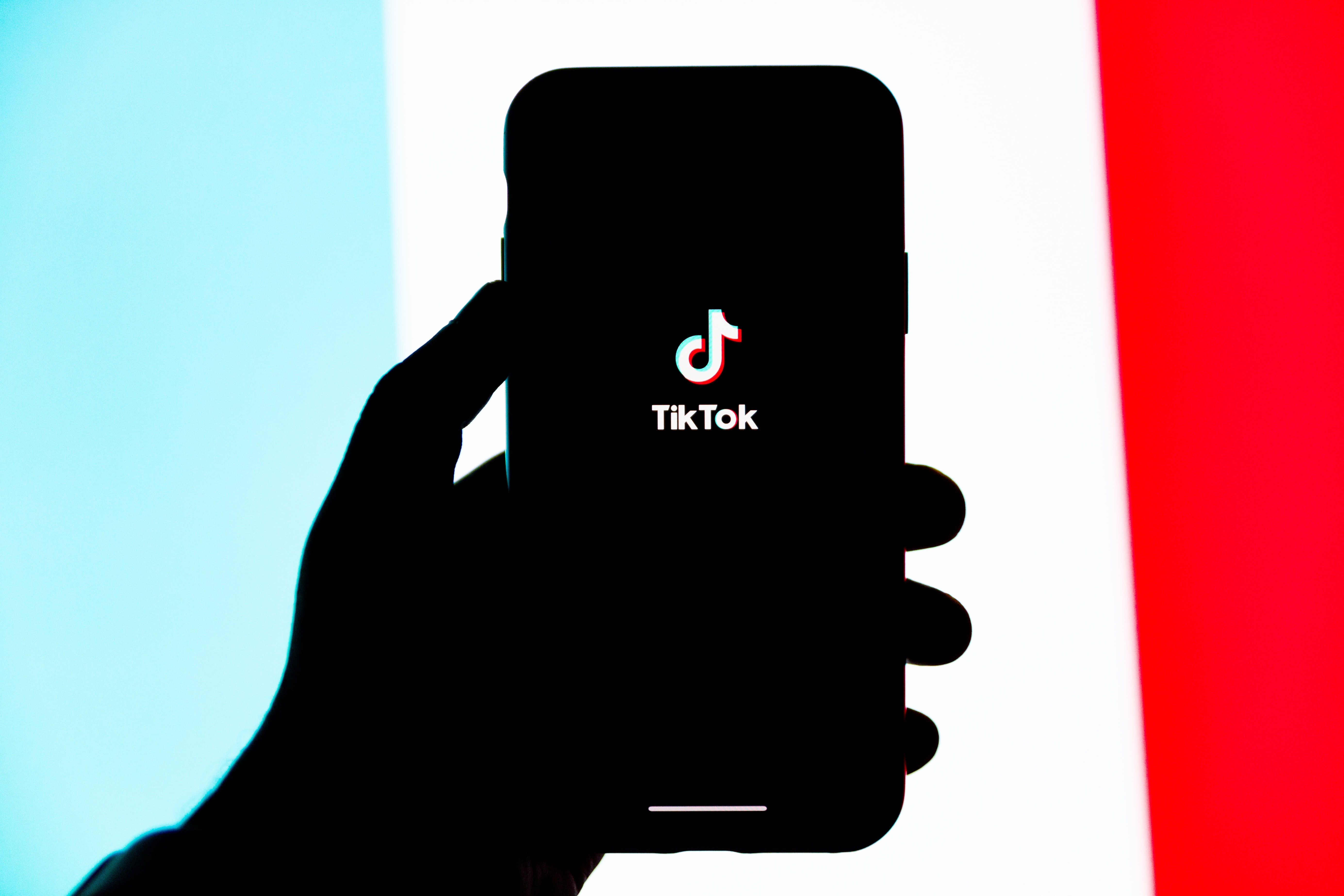 Ei hand med ein telefon med logoen til TikTok