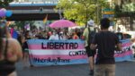 Tog med eit banner for ny translov i Spania, der det står "Libertad" og "#HabráLeyTrans" med fargane til transflagget.
