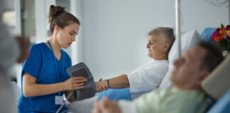 Ung, kvinneleg sjukepleiar måler blodtrykket på ein eldre pasient.