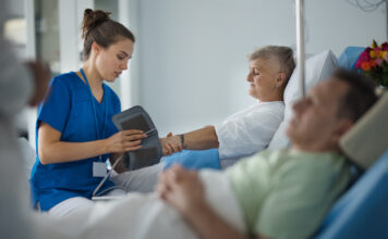 Ung, kvinneleg sjukepleiar måler blodtrykket på ein eldre pasient.