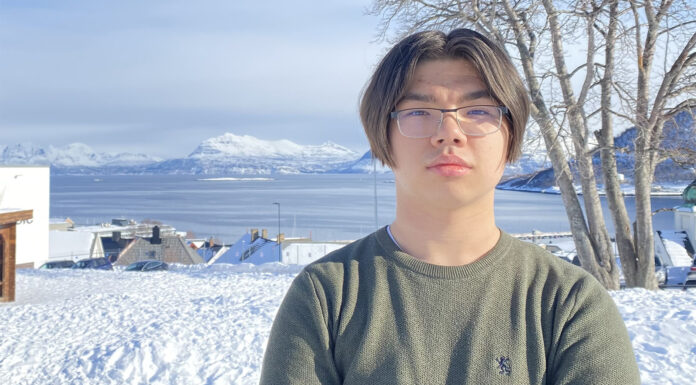 Ungdom med armar i kors i snødekka landskap.