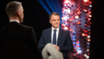 Mann i dress sit i stolen i studioet til Lindmo på NRK 1