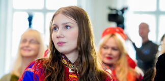Samisk kvinne i fokus ser ut av biletet til venste framfor to andre menneske.