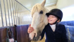 Ung jente med hest i stallen