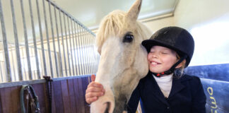 Ung jente med hest i stallen