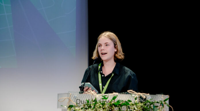 Mira står på talarstolen for Grøn Ungdom og snakkar