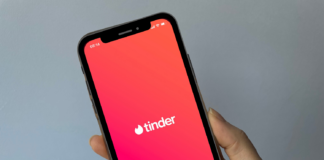 Hand som held ein telefon med Tinder-appen