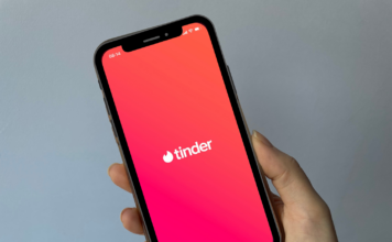 Hand som held ein telefon med Tinder-appen
