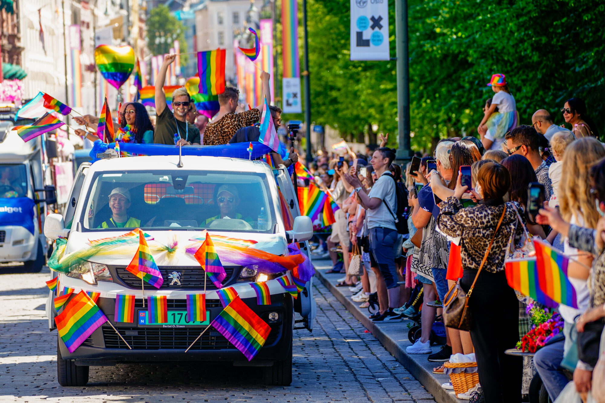 Bil med regnbogeflagg køyrer i paraden.