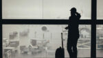 Vaksen mann ser gjennom vindauget på ein flyplass