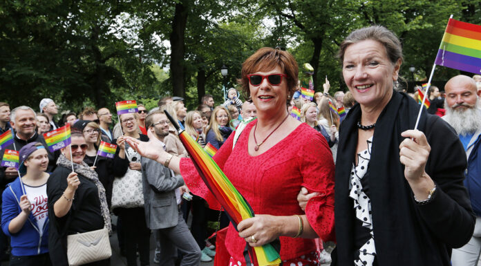 To personar med regnbogeglagg og paraply i pride-parade.
