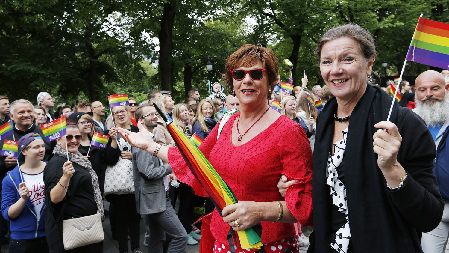 To personar med regnbogeglagg og paraply i pride-parade.