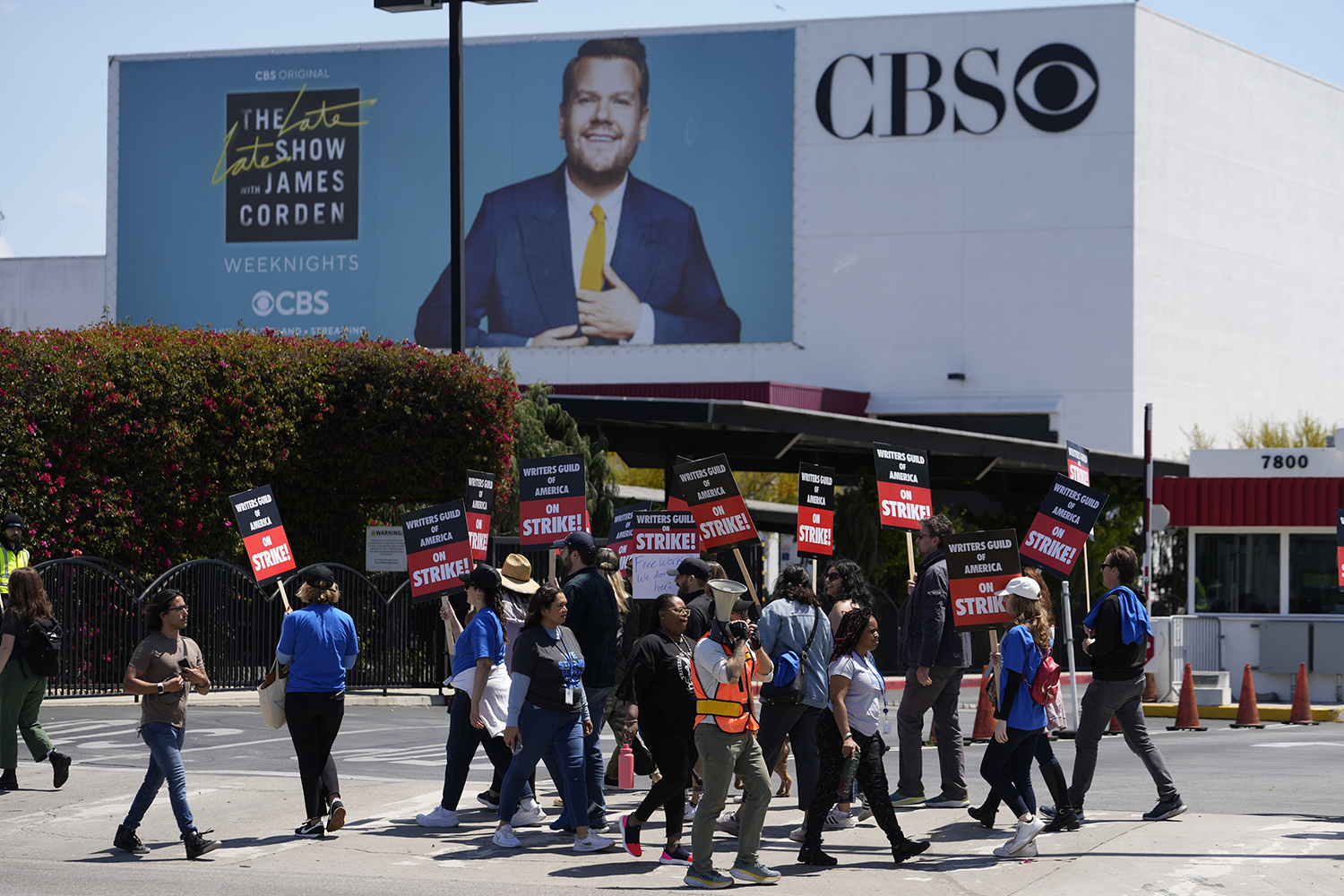 Ei folkemengde med skilt og ropert framfor eit billboard på ein bygning der det står CBS.