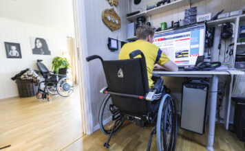 Ung mann i rullestol sit framføre ein PC-skjerm.