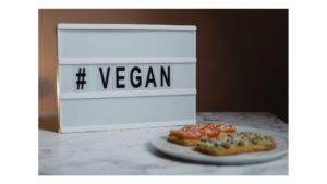 Det står "#Vegan" på ei tavle med ein tallerken med to knekkebrød på pålegg i forgrunnen
