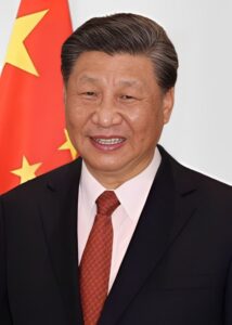 Asiatisk mann i dress med det kinesiske flagget i bakgrunnen.