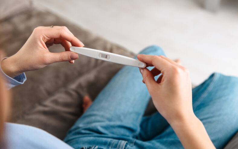 Kvinne held ein positiv graviditetstest