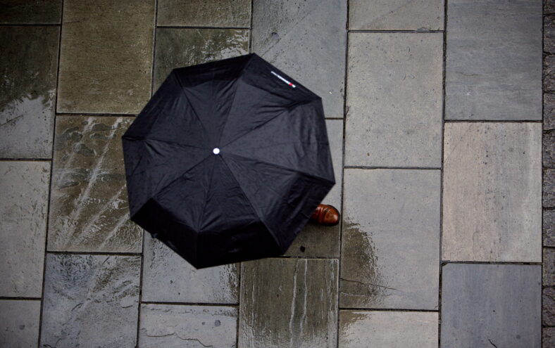 Ein paraply sett ovanfrå i ei våt gate.