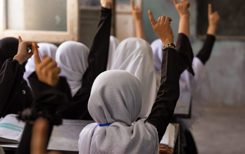 Jenter med hovudplagg i klasserom som rekker opp handa.