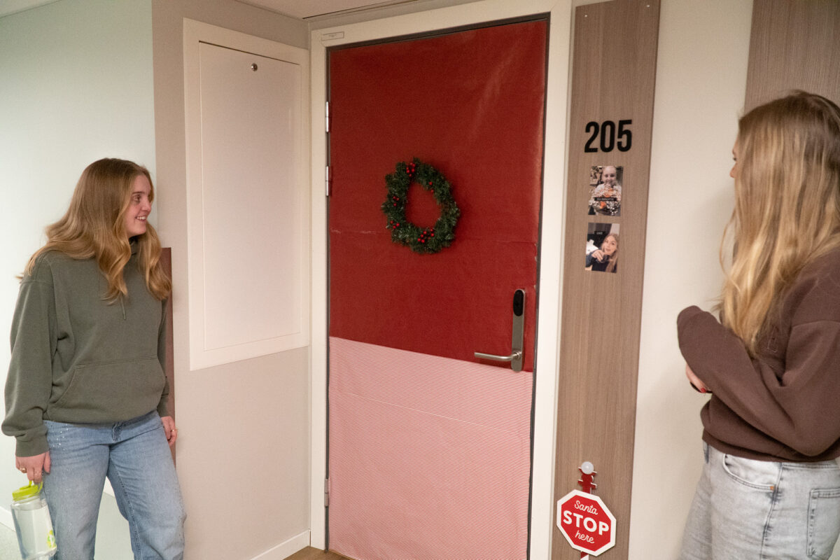 To jenter som ser på ei dør som er dekka i juledekor.