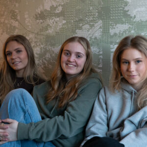 Tre jenter som smiler til kamera.