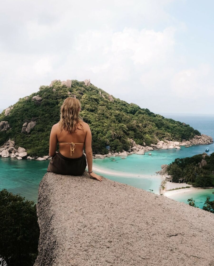 Ei dame sitter på ein stein mot ei øy i Thailand.