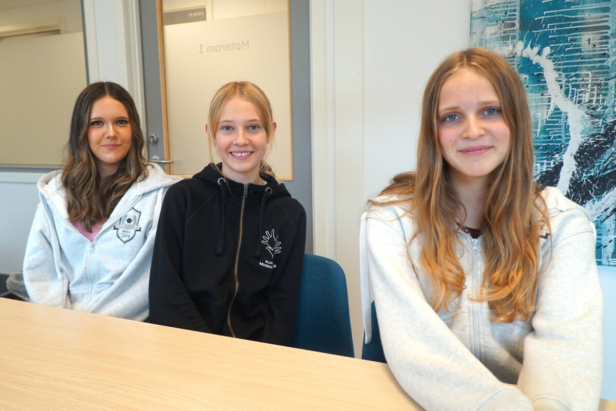 Tre jenter smiler til kameraet.