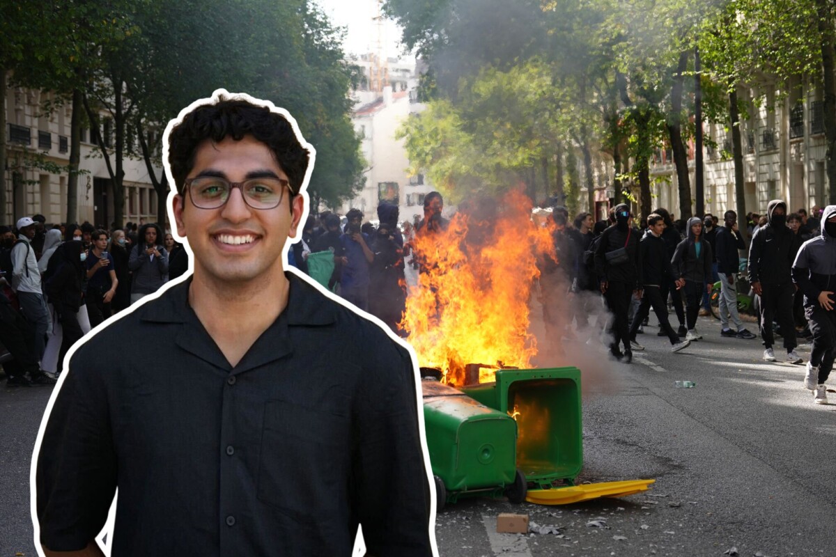 Ein gutt smiler i forgrunnen av ein søppelkasse som brenn.