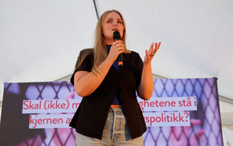 Jente pratar i mikrofon på scene